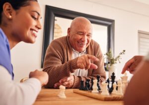 Senior man playing chess with friend and nurse next to them both