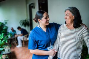 Smiling caregiver talking to a senior woman at nursing home