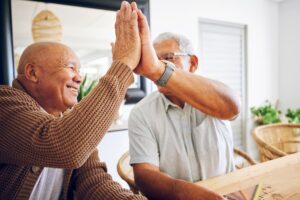 Two senior men giving each other a high five.